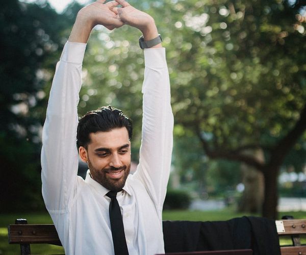 A person smiling and stretching outdoors in a park, feeling refreshed.